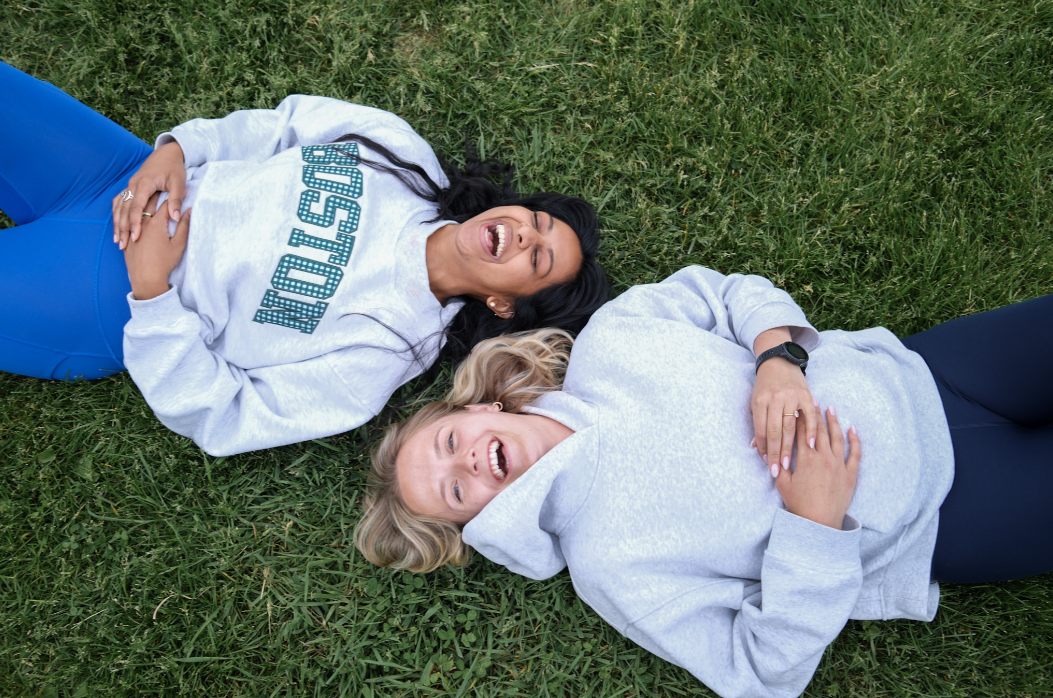 Two women laying in tall grass after a run.